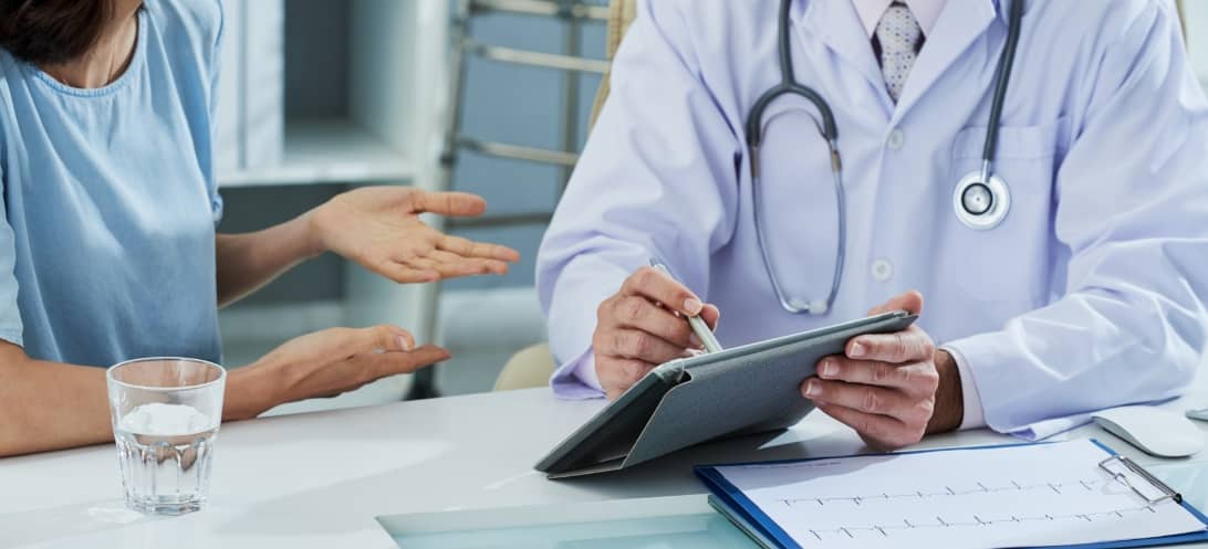 doctor-pointing-digital-tablet-screen-while-explaining-something-patient